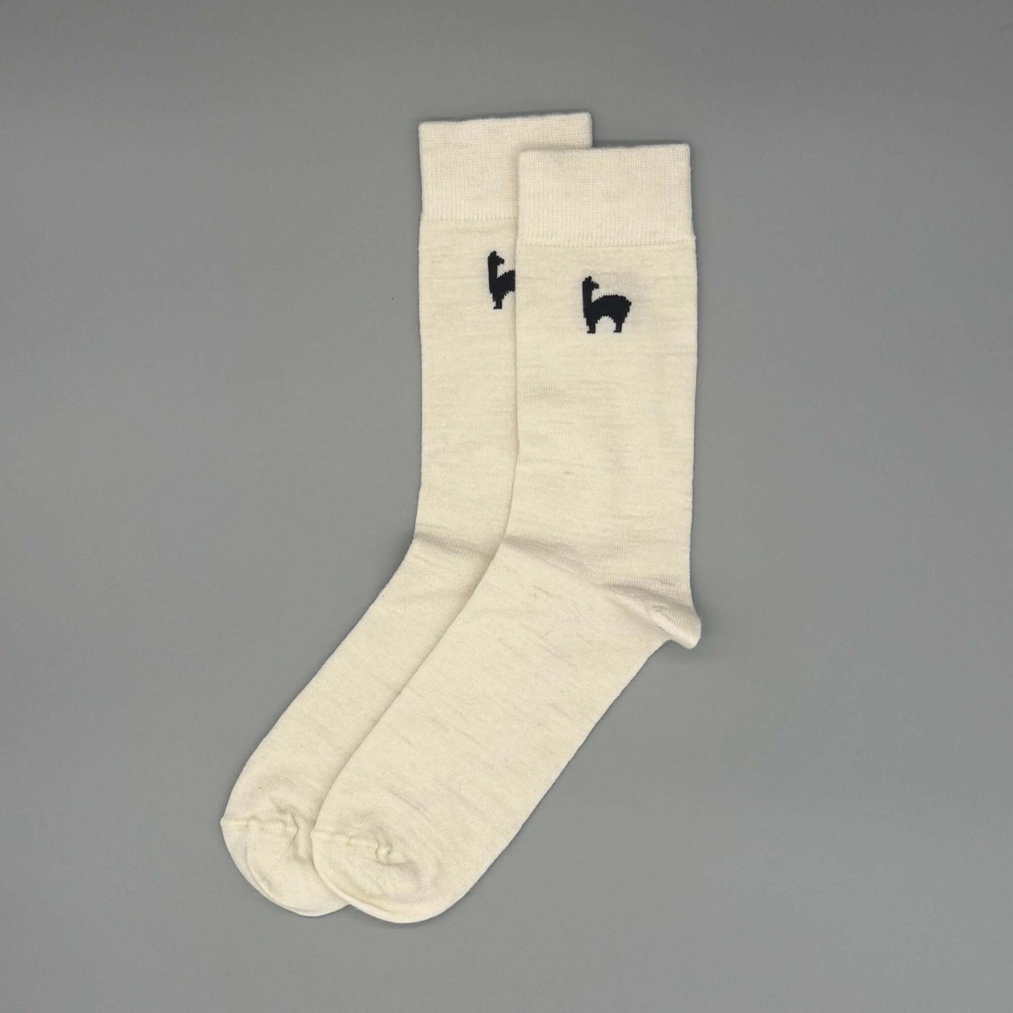 Lange Alpakasocken aus 80% Baby-Alpakawolle in Weiß mit schwarzem Lama-Design für Alltag und Freizeit.
