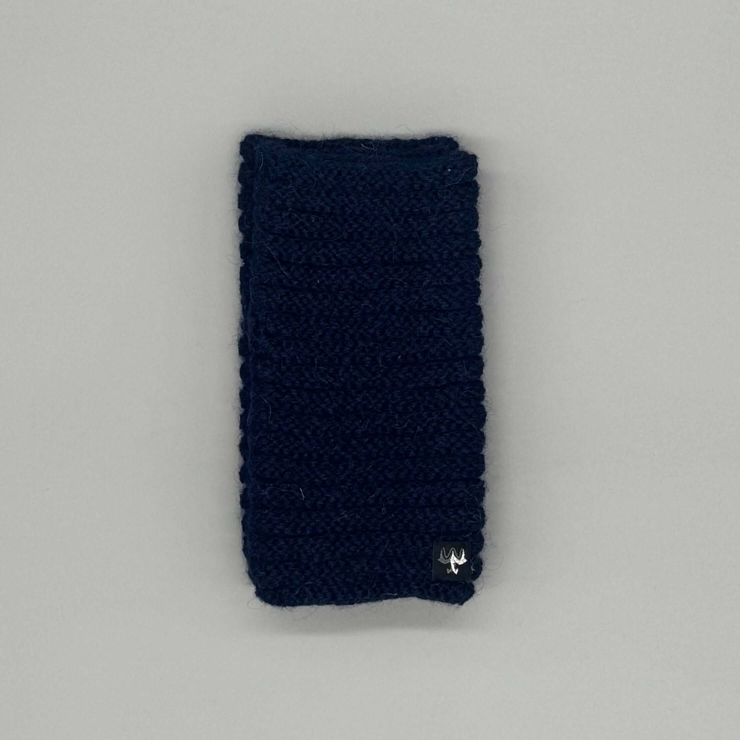 Alpaka Pulswärmer aus Baby-Alpakawolle im Röllchenmuster in Navy auf grauem Hintergrund.