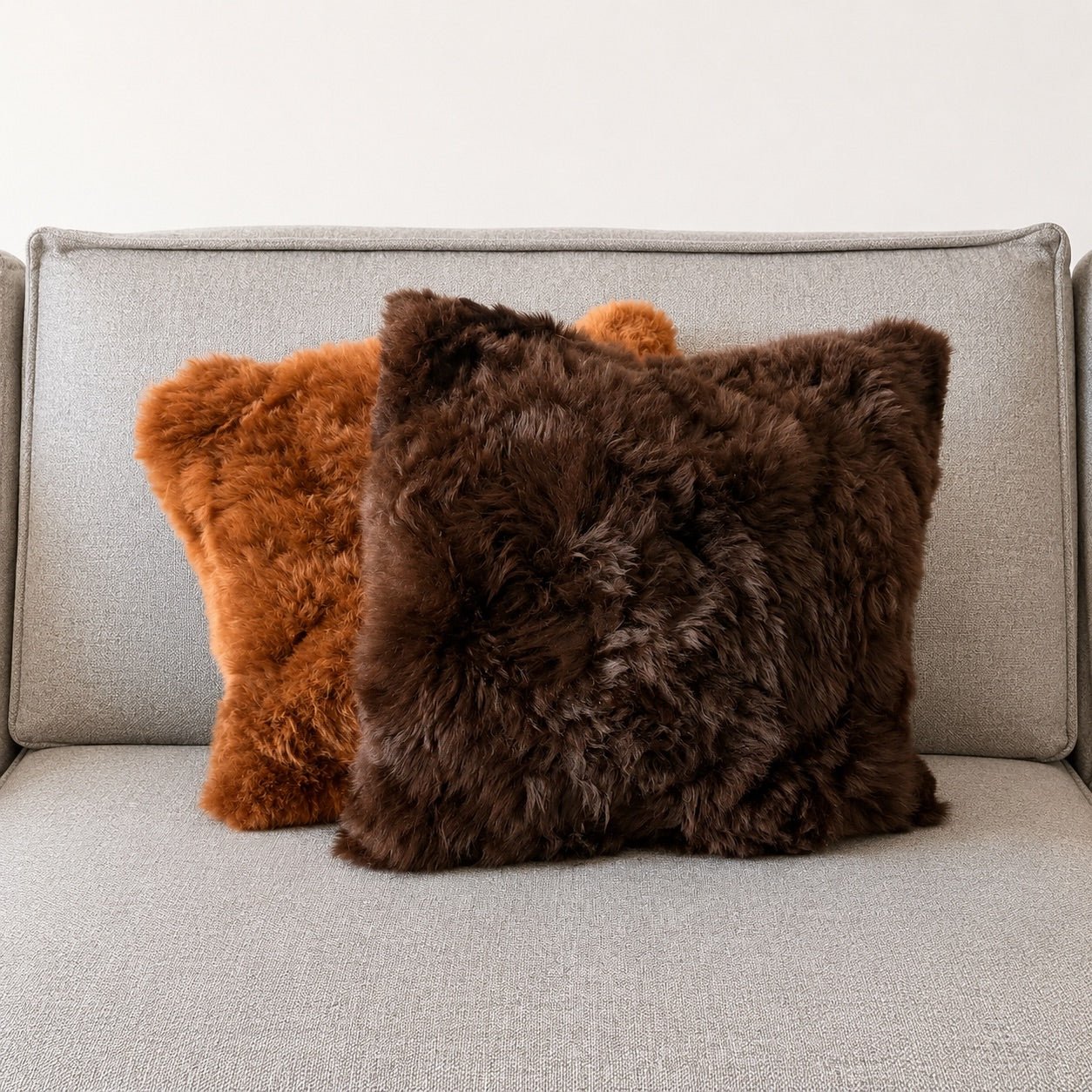 Echtfell Kissenbezug aus 100% Alpaka in Dunkelbraun und Braun auf einem Sofa.