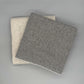 Moderne 130 x 180 cm Sofadecke Baby Alpaka Wolle in Beige und Grau auf grauem Hintergrund.