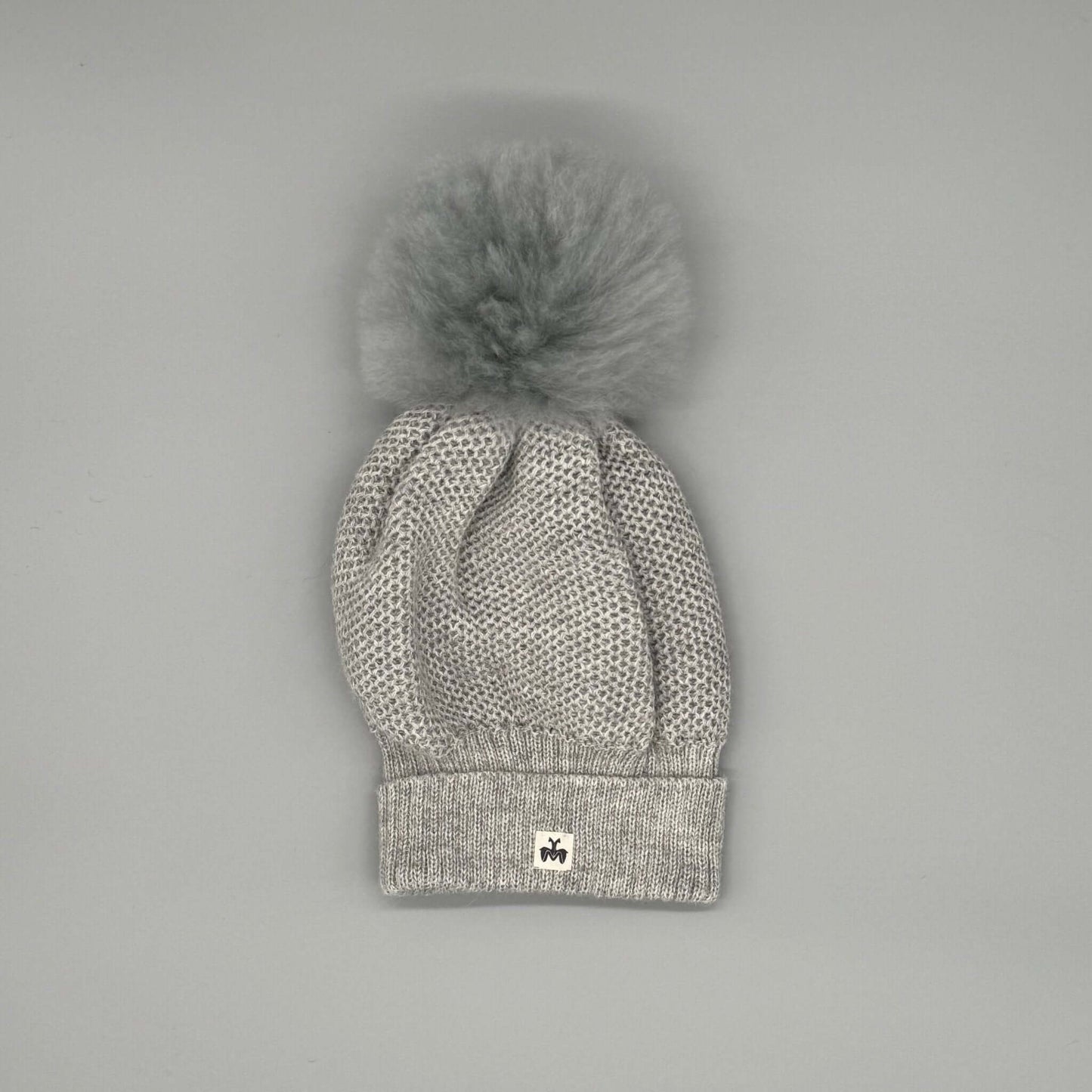 Alpakamütze mit Bommel aus 100 % Alpaka Echtfell in Grau mit feinem Strickmuster und stylishen Bommel.