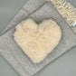 Alpaka Herzkissen aus Alpakawolle auf grauem Schal, flauschiges Kuschelkissen in Herzform.