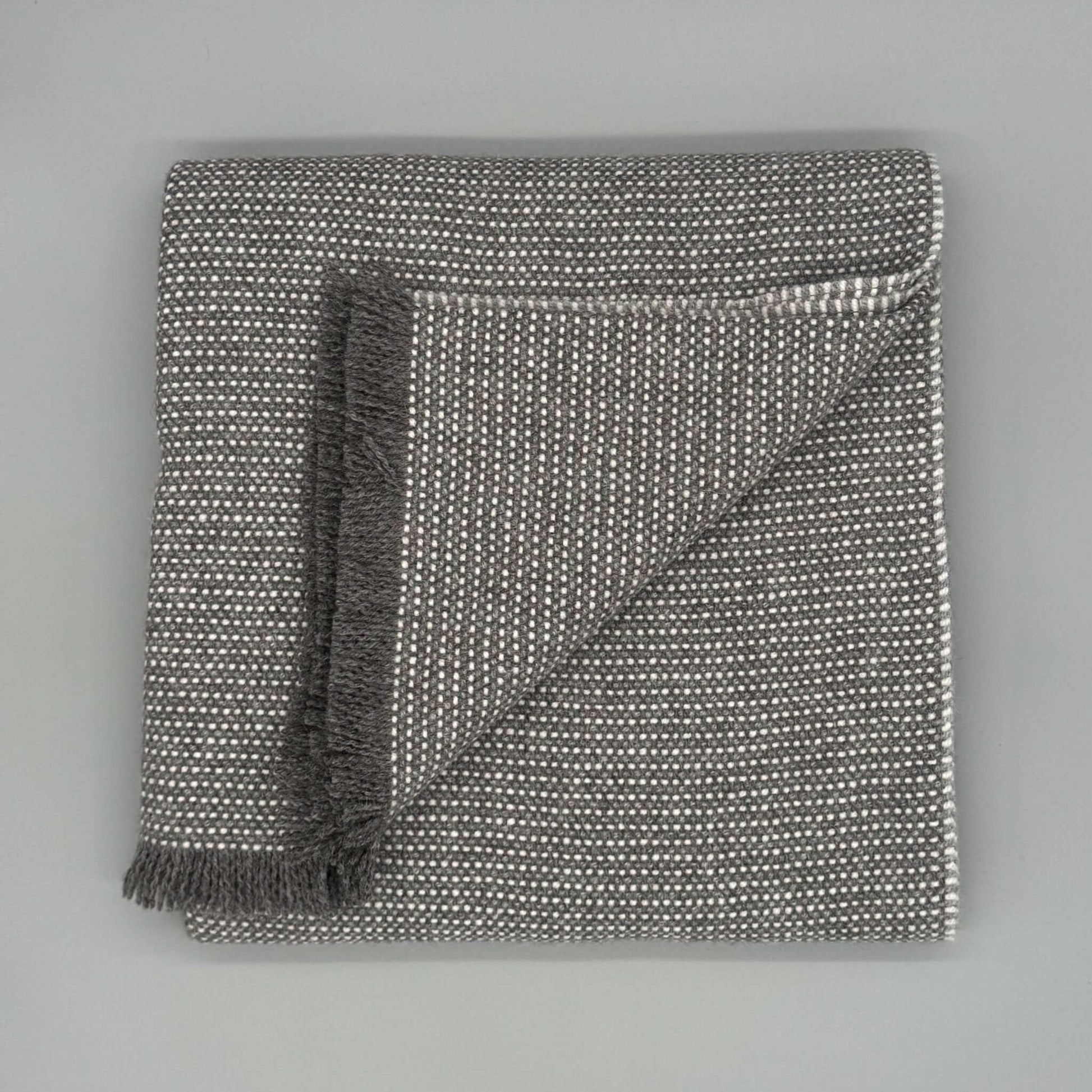 Moderne Sofadecke Baby Alpaka Wolle in Beige und Grau mit feiner Webstruktur und fransigem Saum.